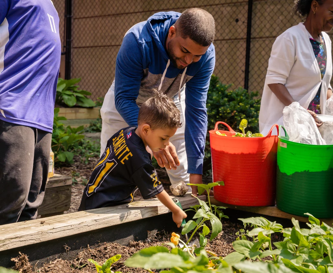 A father helps his son garden at Creston Ave Community Playground